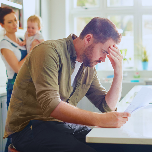 man frustrated looking over paperwork while wife and child look on